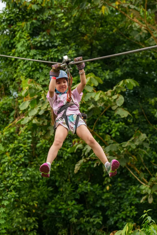 A young traveller riding a zipline over the rainforest canopy