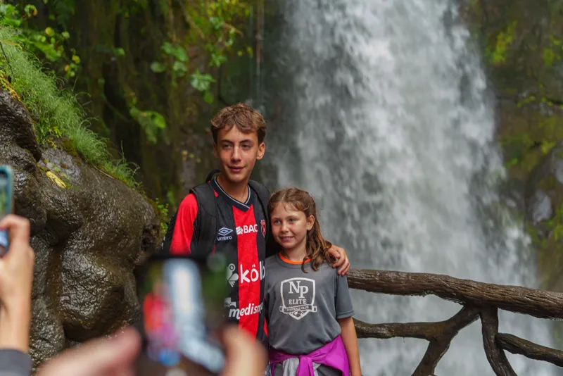 Two young players in front of a waterfall at La Paz Waterfall Gardens